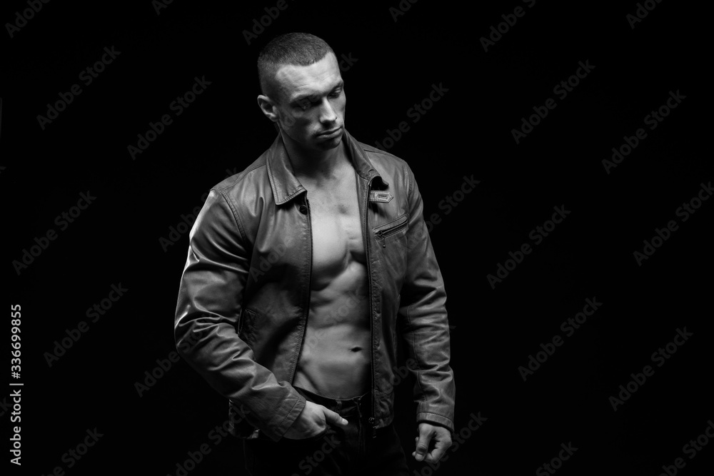 Sexy torso.  Fashion portrait of sporty healthy strong muscle guy.  Muscular model sports young man in jeans showing his press on a black background. Black and white photography
