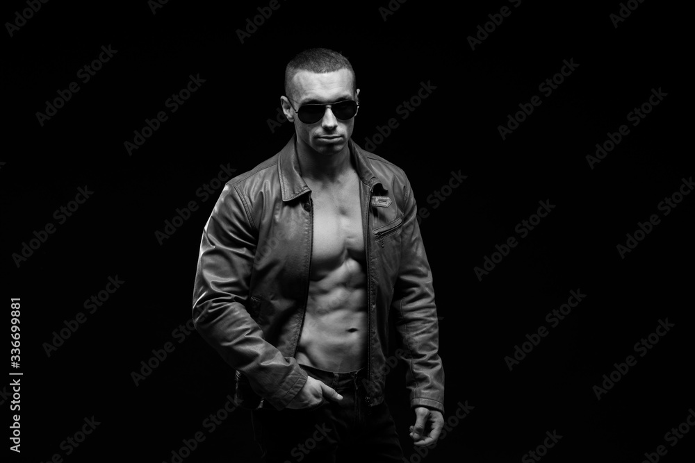 Obraz premium Sexy torso. Fashion portrait of sporty healthy strong muscle guy. Muscular model sports young man in jeans showing his press on a black background. Black and white photography 