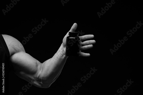 Muscular bodybuilder with jar of protein on a dark background. Sports nutrition. Bodybuilding nutrition supplements, sport, workout, healthy lifestyle concept.