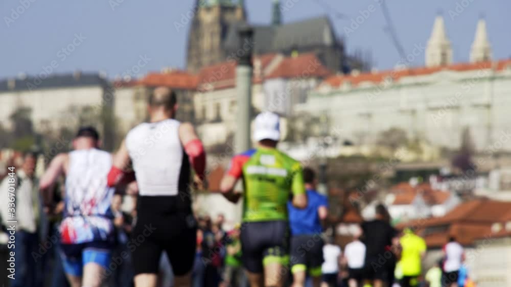 Background concept shot, Back view blurry amateur runners taking part in Prague half marathon. Unrecognizable people running on city street against famous Prague castle Background concept shot, Back view blurry amateur runners taking part in Prague half marathon. Unrecognizable people running on city street against famous Prague castle