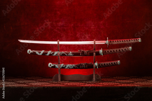 Three swords on stand, katana blade exposed, red