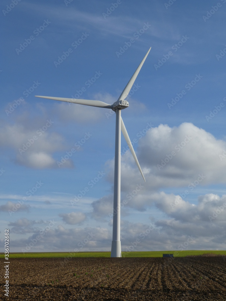 Wind turbine in a field with cottony clouds in the background Wind turbine in a field with cottony clouds in the background