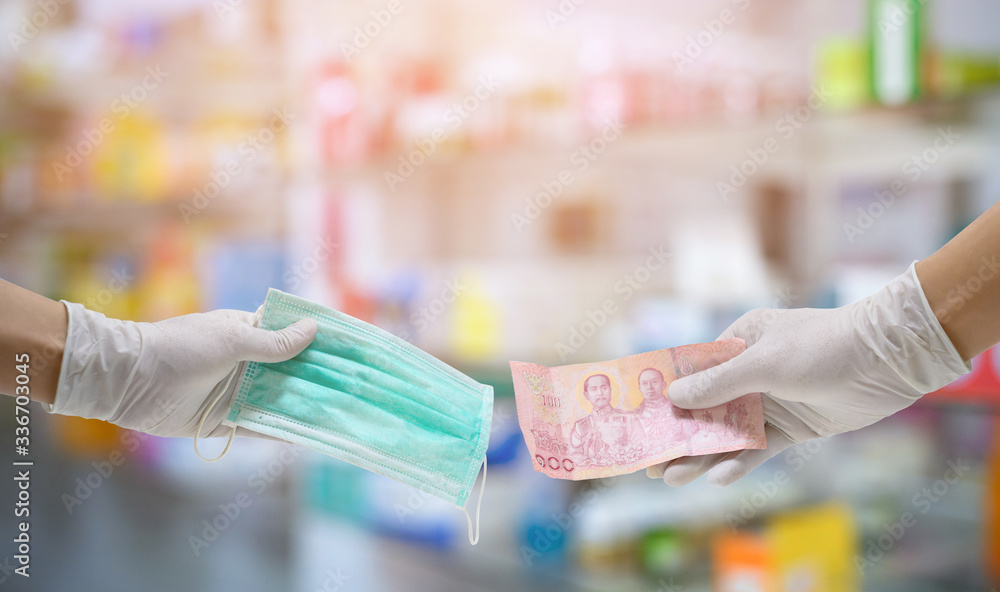 The hand that wears hygiene gloves holds money and holds a mask. Purchase a surgical mask.