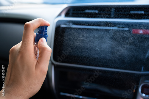 Man is spraying alcohol,disinfectant spray in car for prevention coronavirus disease (covid-19) contamination of germs and wipe clean surface, health care concept (select focus)