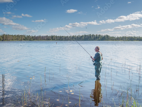 Karelia, Vodlozero - 29.07.2019: Man fishing with spinning in a lake. Ecotourism, visiting fragile, pristine, undisturbed natural areas