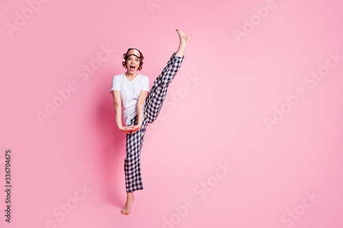 Full body photo of funny lady raise leg high slumber night party presenting perfect exciting agility wear sleep mask white t-shirt checkered pajama pants isolated pink color background