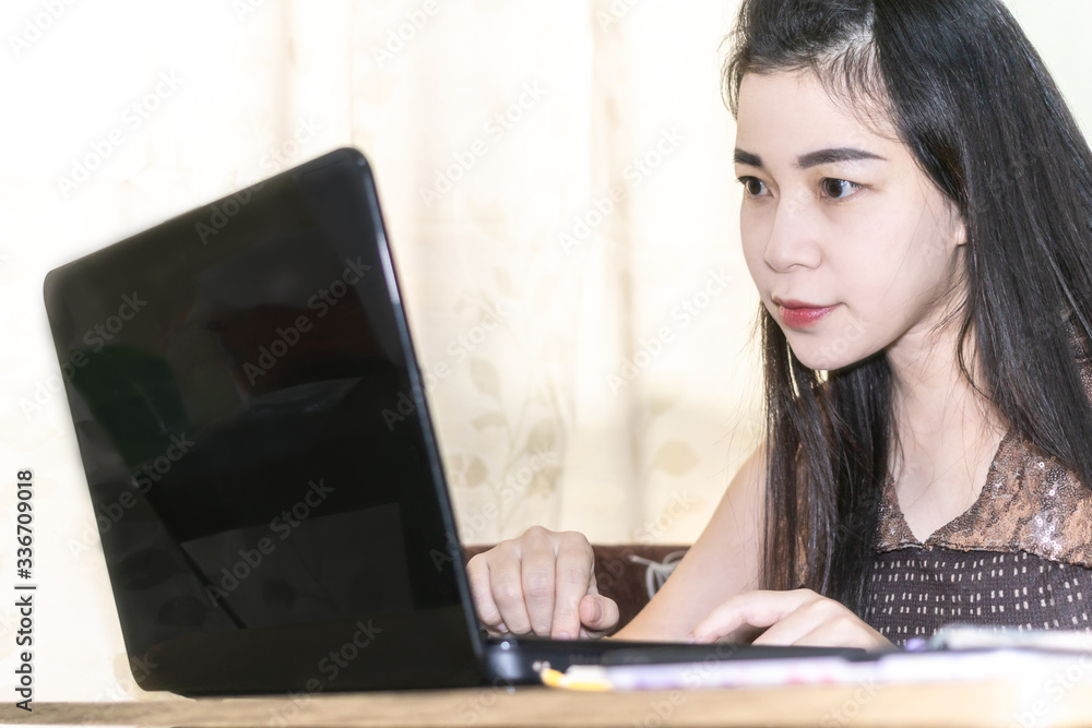 Happy young woman working and learning online from computer. Beautiful woman sitting on sofa looking at laptop. work from home concept.