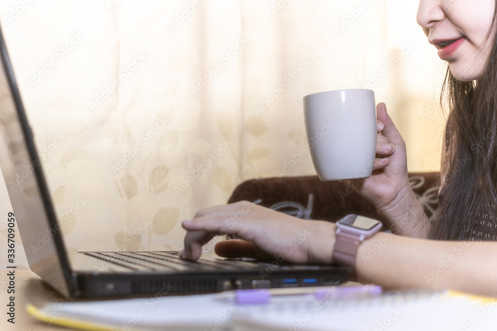 Happy young woman working and learning online from laptop while sitting at the living room, drinking coffee. work from home concept. Happy young woman working and learning online from laptop while sitting at the living room, drinking coffee. work from home concept.