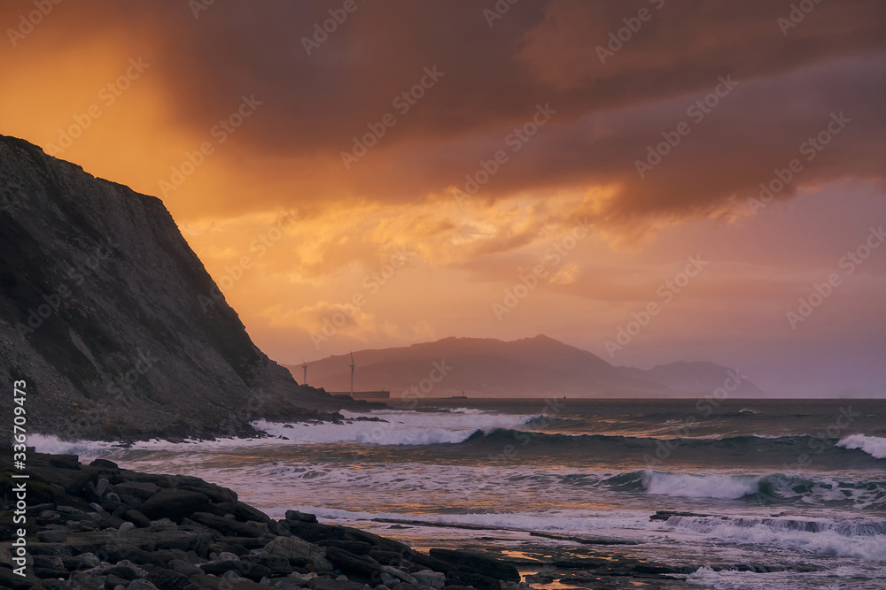 Azkorri (Getxo Basque Country) beach at sunset Orange sunset with rocks waves sea Storm