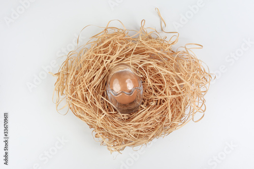 Egg in egg shape glass container protection shell on white background safety security straw nest