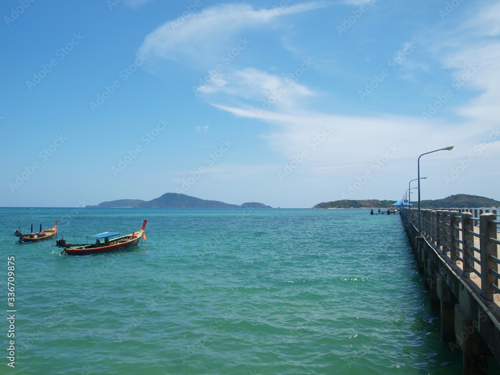 The sea and islands of Thailand. Two traditional longtail fishing boats. Longtailboat. Two old wooden fishing schooners are anchored near the pier. The pier extends to the horizon. Panorama, seascape.