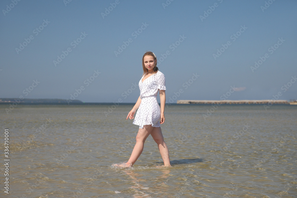 Happy young girl in white dress by the sea
