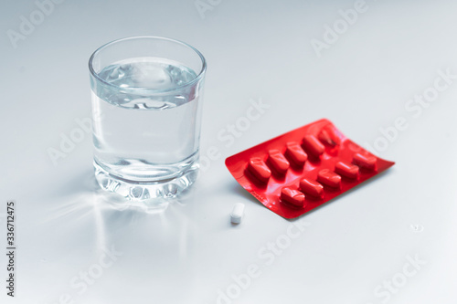 Dramatic medical mood - glass of drinking water and pills (tablets or drugs) on the table. Close up