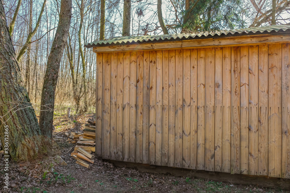 Chopped firewood near a wooden house on a sunny day in Ukraine. Firewood stacked on the ground. Little house in the forest. Chopped firewood near a wooden house on a sunny day in Ukraine. Firewood stacked on the ground. Little house in the forest.