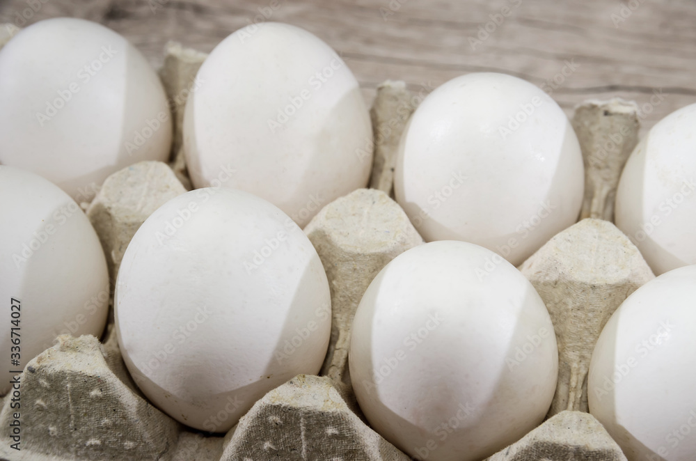 white chicken eggs in a tray on a wooden table. white chicken eggs in a tray on a wooden table.