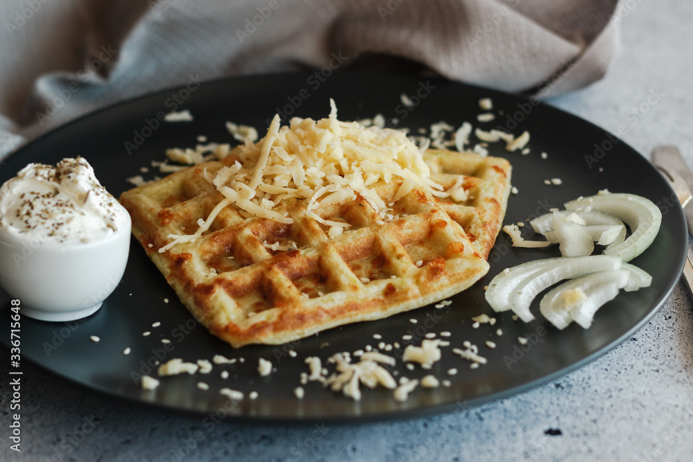 Tasty waffles with zucchini and cheese. Waffles served with cheese, onions, sour cream and spices. Waffles on a plate Tasty waffles with zucchini and cheese. Waffles served with cheese, onions, sour cream and spices. Waffles on a plate