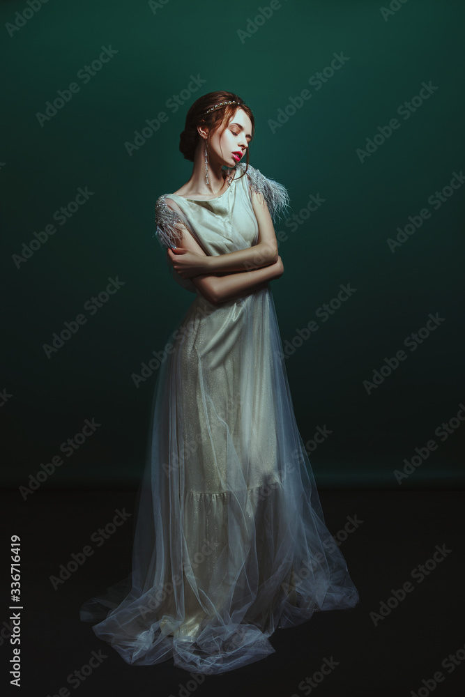 Fototapeta premium Emotional old-fashioned portrait of a girl in retro style in a light transparent dress with shiny elements on the shoulders.