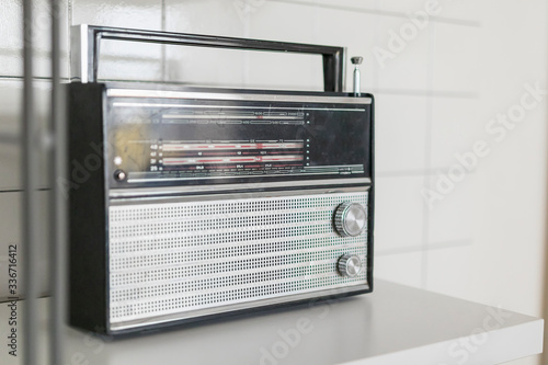 an old Soviet radio receiver from Russia in black with a silver grille on a white shelf