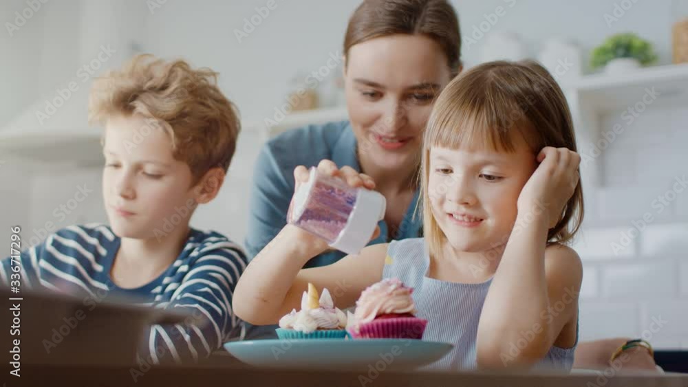 In the Kitchen: Portrait of the Young Mother and Cute Little Daughter Sprinkling Funfetti on Creamy Cupcakes Frosting. Family Cooking Muffins Together. Adorable Children Helping their Caring Parents
In the Kitchen: Portrait of the Young Mother and Cute Little Daughter Sprinkling Funfetti on Creamy Cupcakes Frosting. Family Cooking Muffins Together. Adorable Children Helping their Caring Parents