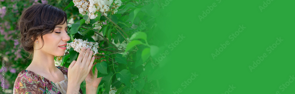 Fototapeta premium Beautiful young girl is surrounded by flowers of Lilac. Cosmetic products for skin care. Health, beauty, cosmetics concept banner