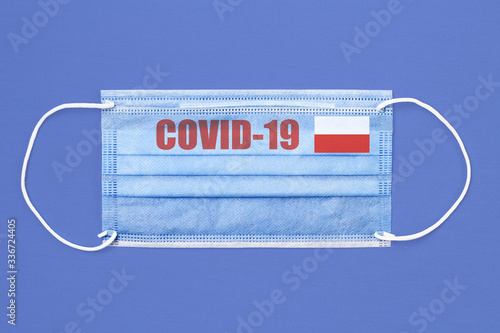 Medical mask and text or inscription Covid-19. Coronavirus pandemic concept. Flag of Poland. photo