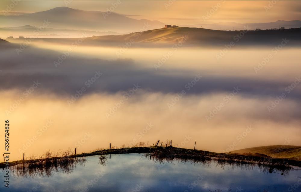 a misty sunrise shot from torre a castello in the crete senesi landscape a misty sunrise shot from torre a castello in the crete senesi landscape