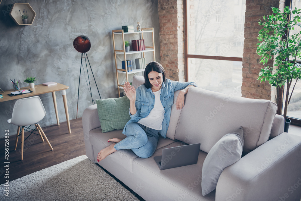 Stay home concept. Photo of pretty lady home alone quarantine time watch notebook waving arm skype video talk relatives friends distance work remote sit comfortable sofa living room indoors Stay home concept. Photo of pretty lady home alone quarantine time watch notebook waving arm skype video talk relatives friends distance work remote sit comfortable sofa living room indoors