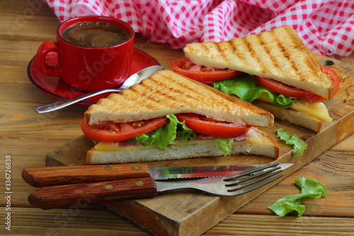 Sandwich with tomatoes, cheese and ham on a dark, wooden background