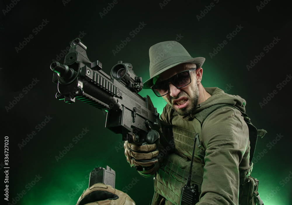 a sporty guy poses with an automatic rifle