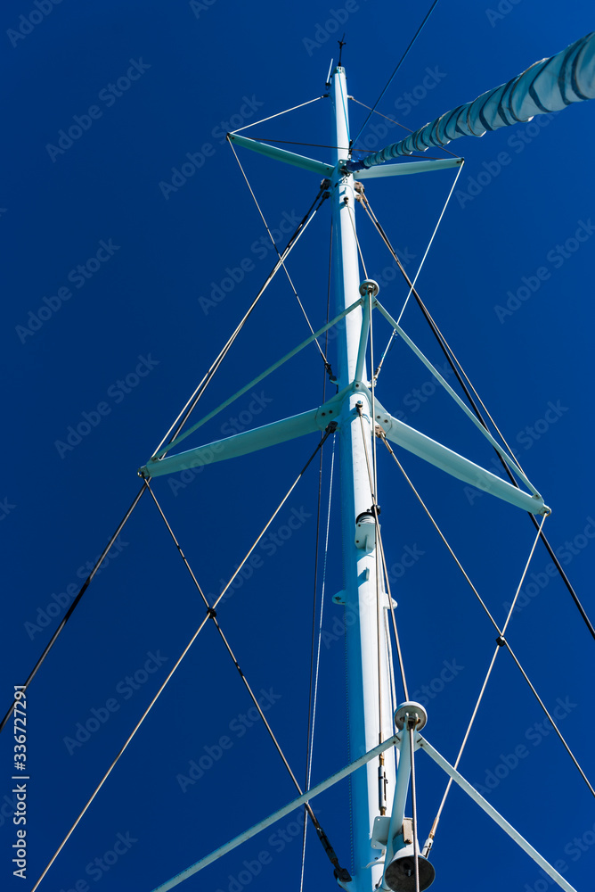 detail of tall ship mast of sailing boat with rigging on blue background detail of tall ship mast of sailing boat with rigging on blue background
