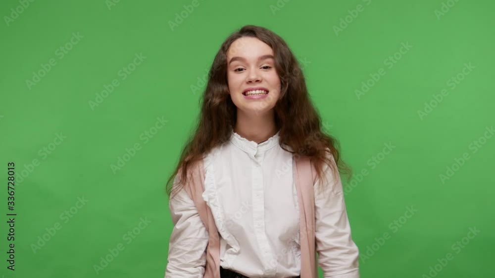 Hey, we need you! Charming cute teenage brunette girl in white shirt pointing finger guns to camera and winking, showing her choice with hand pistols. indoor studio shot isolated on green background Hey, we need you! Charming cute teenage brunette girl in white shirt pointing finger guns to camera and winking, showing her choice with hand pistols. indoor studio shot isolated on green background