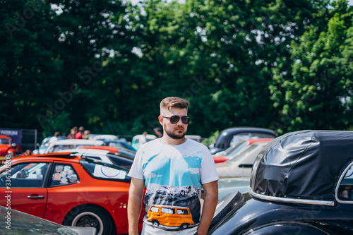 Handsome man in sunglasses near retro cars.