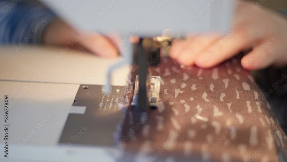 Close up of woman fingers sew on sewing machine. Details of sewing machine Close up of woman fingers sew on sewing machine. Details of sewing machine