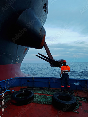 Bow of a tanker ship vessel with seaman looking at the anchor