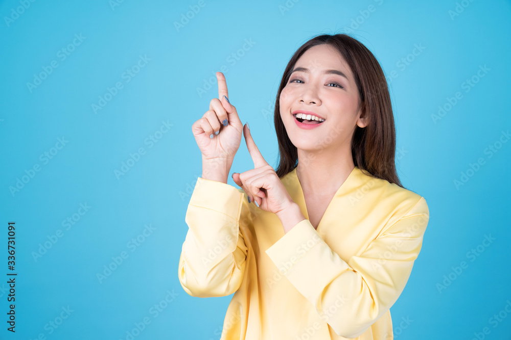 Young beautiful asian woman pointing to copy space, isolated on blue background. Young beautiful asian woman pointing to copy space, isolated on blue background.