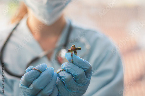 Canvas Print female doctor is holding a crucifix in her hand and she is praying