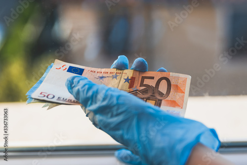 human hands wearing surgical gloves is manipulating euro bills