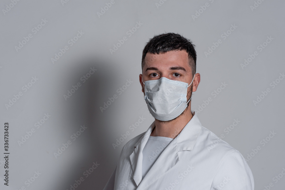 portrait of a brunette man doctor in a white coat with a mask on his face on a white background portrait of a brunette man doctor in a white coat with a mask on his face on a white background