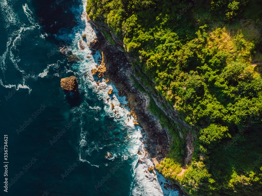 Aerial view of cliff and ocean with waves in Bali.