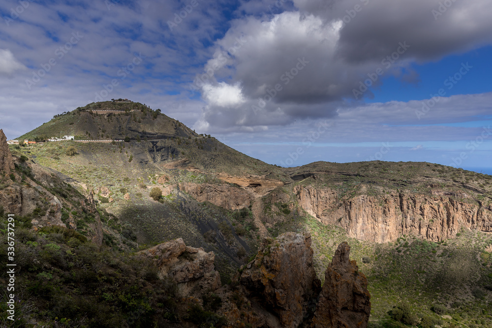 Obraz premium View of the mountainous landscape of volcanic origin along with lots of trees and vegetation and on the horizon, you can see the setting moon Gran Canary island