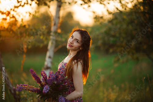 brunette in a flower field.The girl holds lupines purple