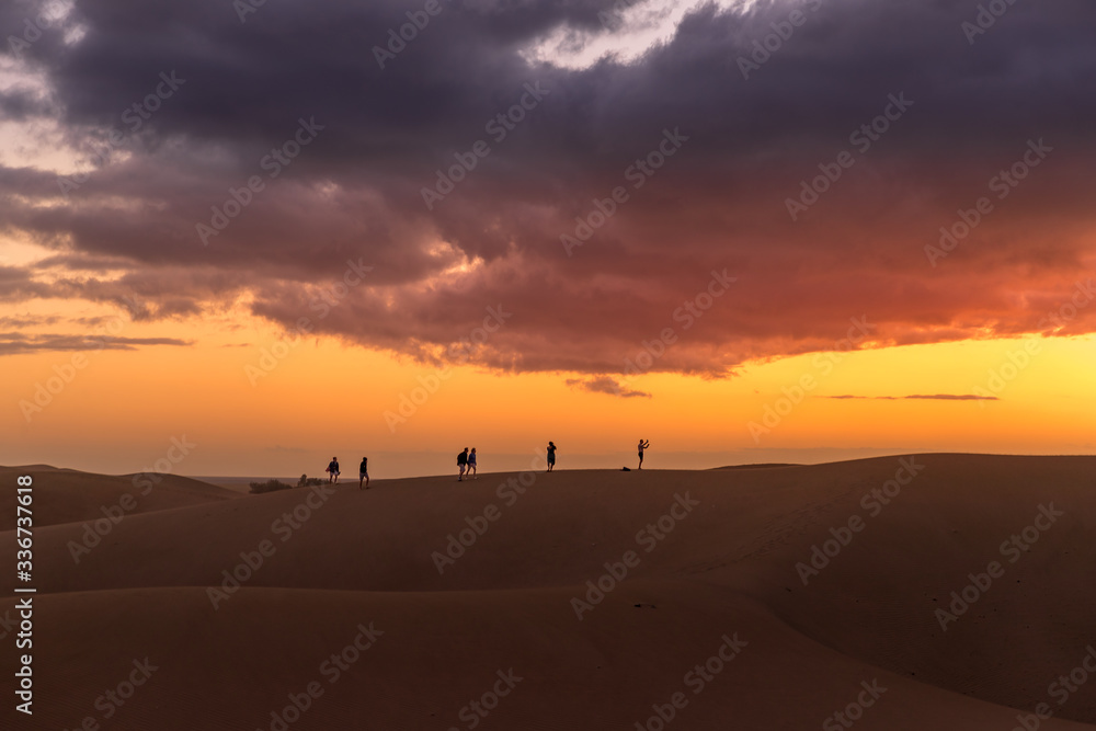 Obraz premium Sand dunes around a city full of people walking down the dunes overlooking the ocean located behind the dunes of Gran Canary island