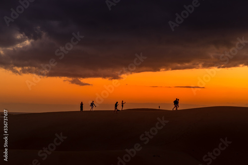 Sand dunes around a city full of people walking down the dunes overlooking the ocean located behind the dunes of Gran Canary island