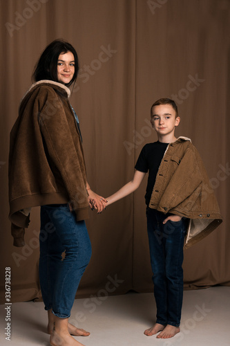 close-up portrait siblings with brown eyes in studio with brown nude texture background have a fun,laghfing, smiling, love each other in brown jackets photo