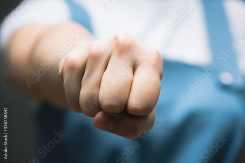 Photos Angry woman in blue dress is shaking her fist close up on gray background