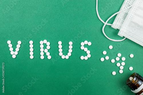 A word VIRUS spelled with white pills on green background. Top view