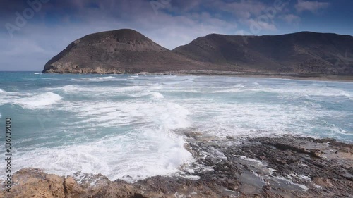 Seascape. Beach El Playazo, Cabo de Gata, province AlmerĂ­a, Andalusia Spain. Rocky sea shore with waves splashing in slow motion. Tourist site photo