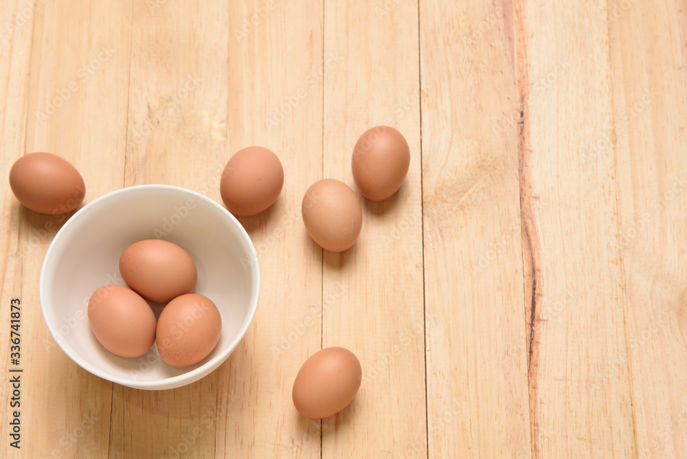 Three eggs and white cup on wooden background, top view and copy space for text Three eggs and white cup on wooden background, top view and copy space for text