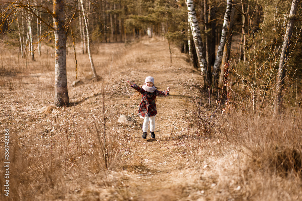 little girl in a coat runs along a forest path