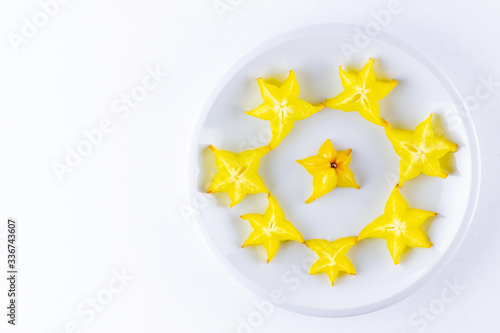 Carambola on a white plate. Sliced fresh carambola on a white background. Slices of star fruit. Trendy food